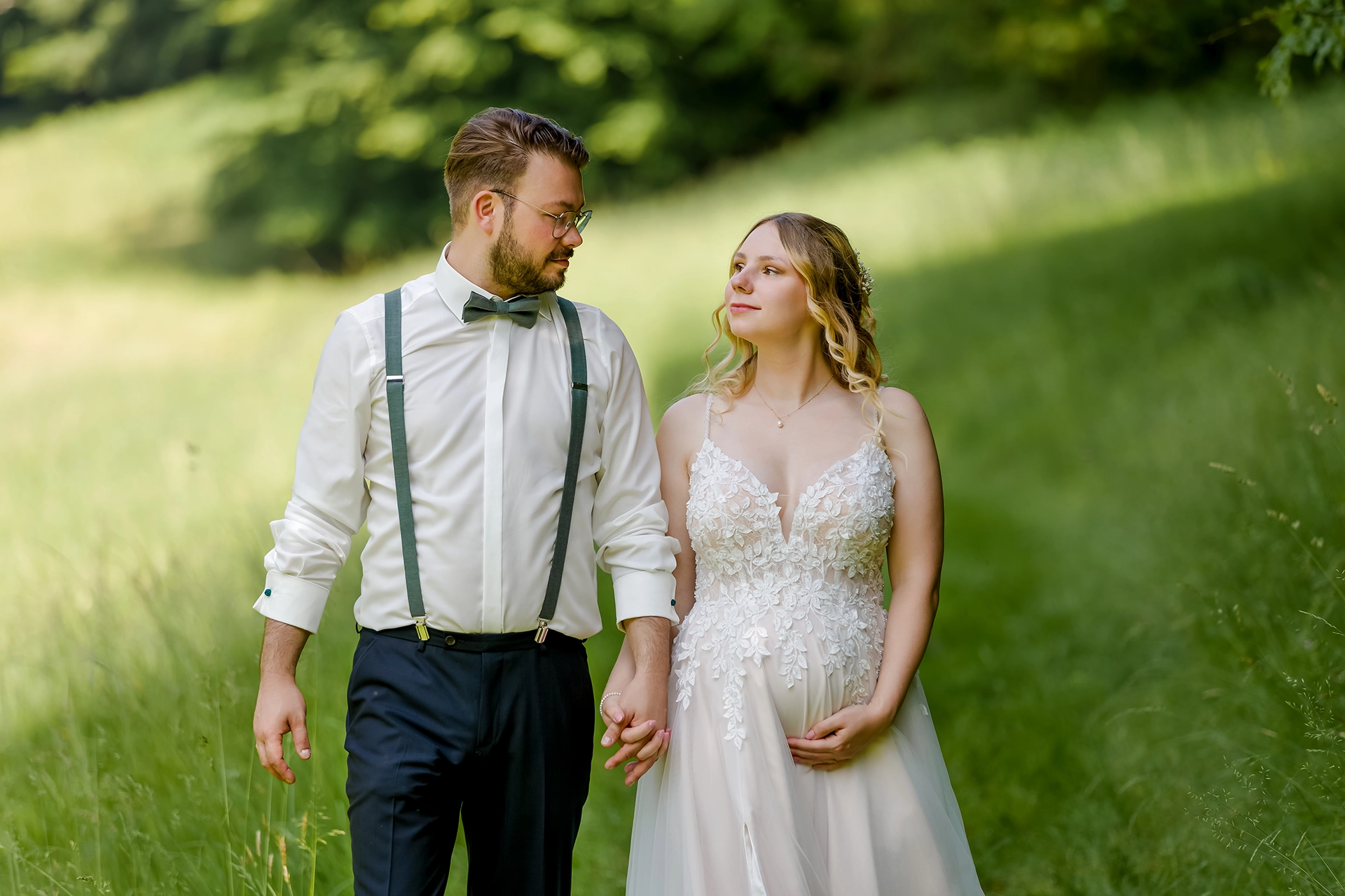 Schwangere Frau hält Babybauch bei Sonnenuntergang